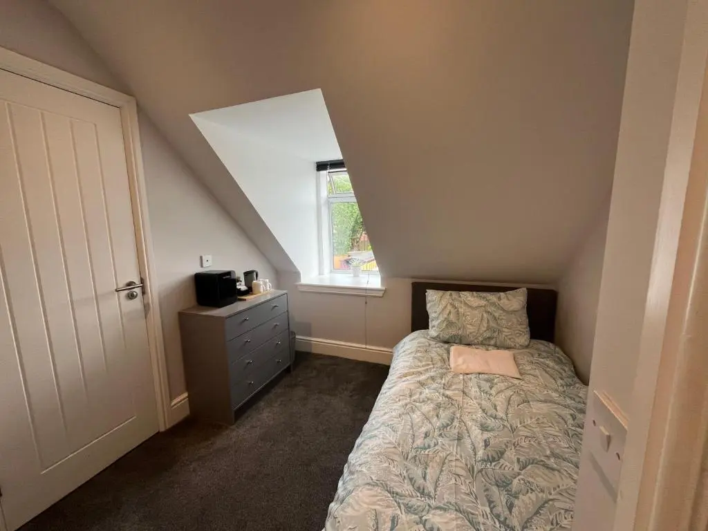a small bedroom with a bed and a window at Fairfield Cottage Rooms in Inverness