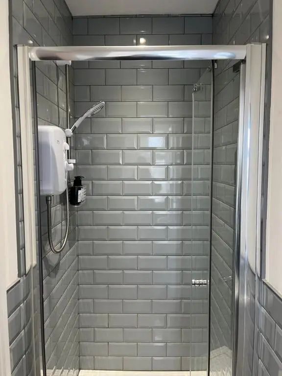 a shower in a bathroom with gray tiles at Fairfield Cottage Rooms in Inverness
