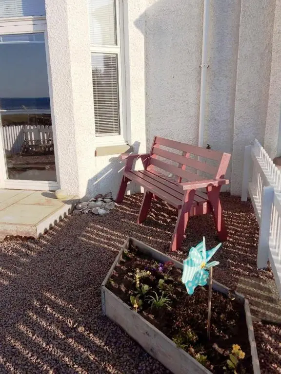 a red bench sitting on the side of a house at Seabreeze in Whitehills