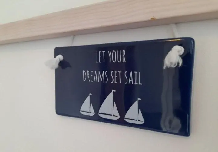 a sign hanging on a wall with three sailboats at Seabreeze in Whitehills