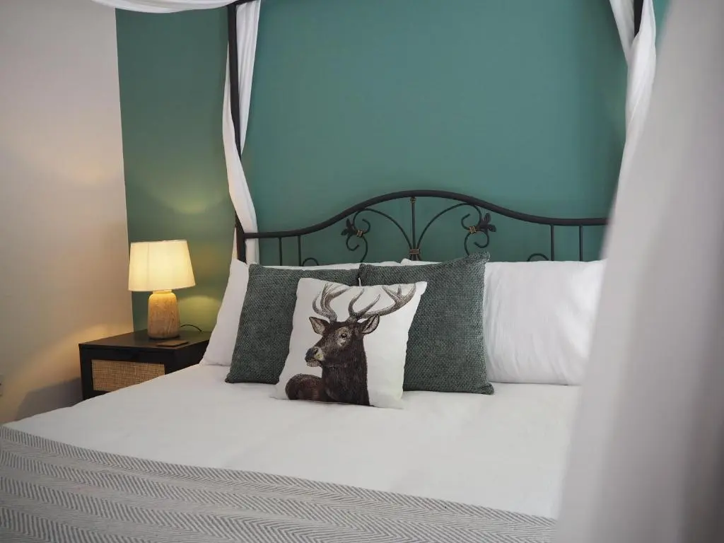 a bedroom with a bed with a deer on the pillows at Coille Burn in Urray