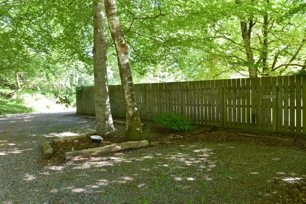 a fence and two trees in front of a yard at Coille Burn in Urray