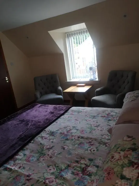 a bedroom with a bed and two chairs and a window at Gladstone Cottage in Inverness