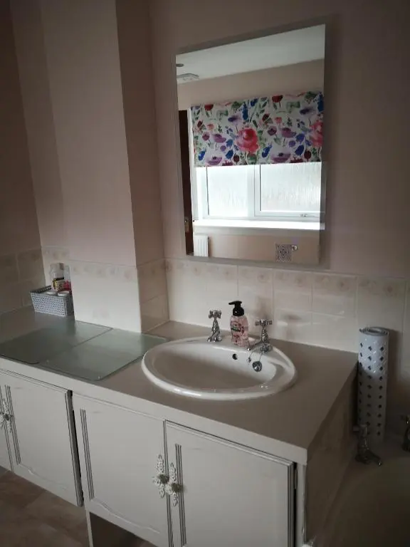 a bathroom with a sink and a mirror at Gladstone Cottage in Inverness