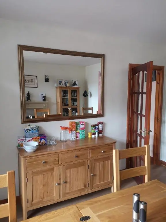 a large mirror on the wall above a wooden dresser at Gladstone Cottage in Inverness