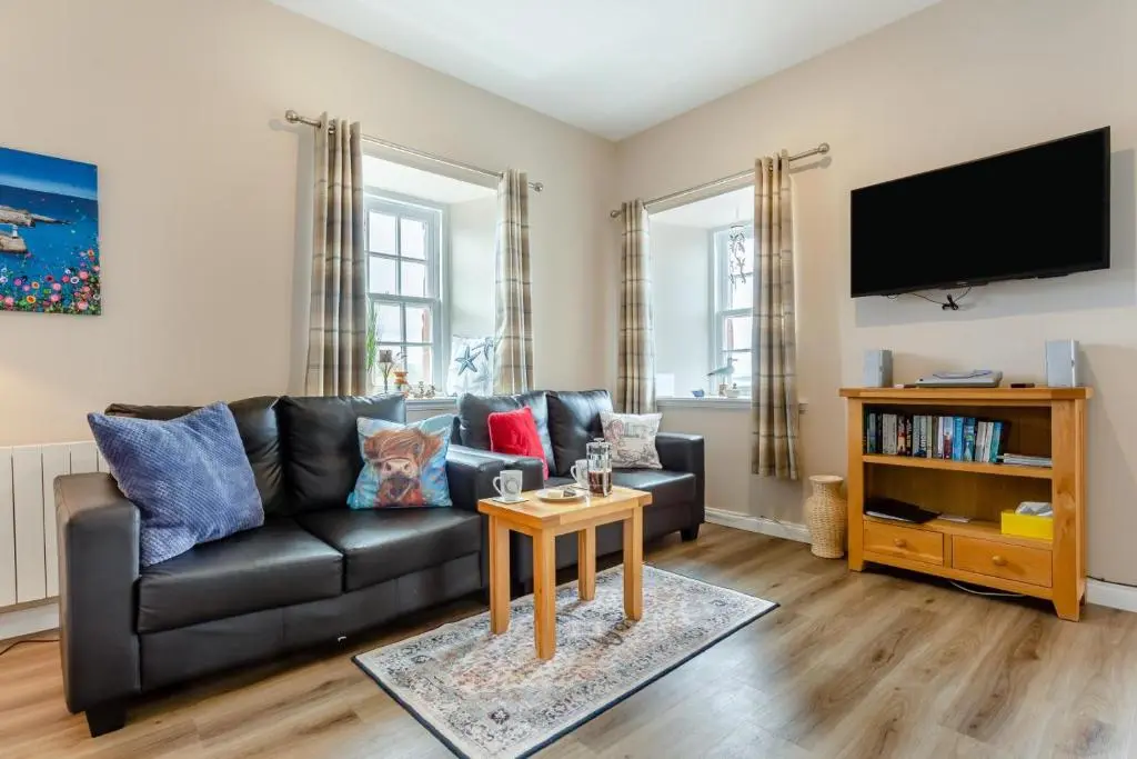 a living room with a black leather couch and a tv at 2 Bed in Cromarty oc-s32047 in Cromarty