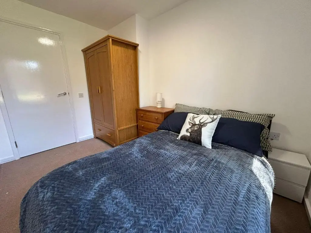 a bedroom with a bed with a blue comforter at Two bedroom cottage in Lumsden - Contractors in Huntly