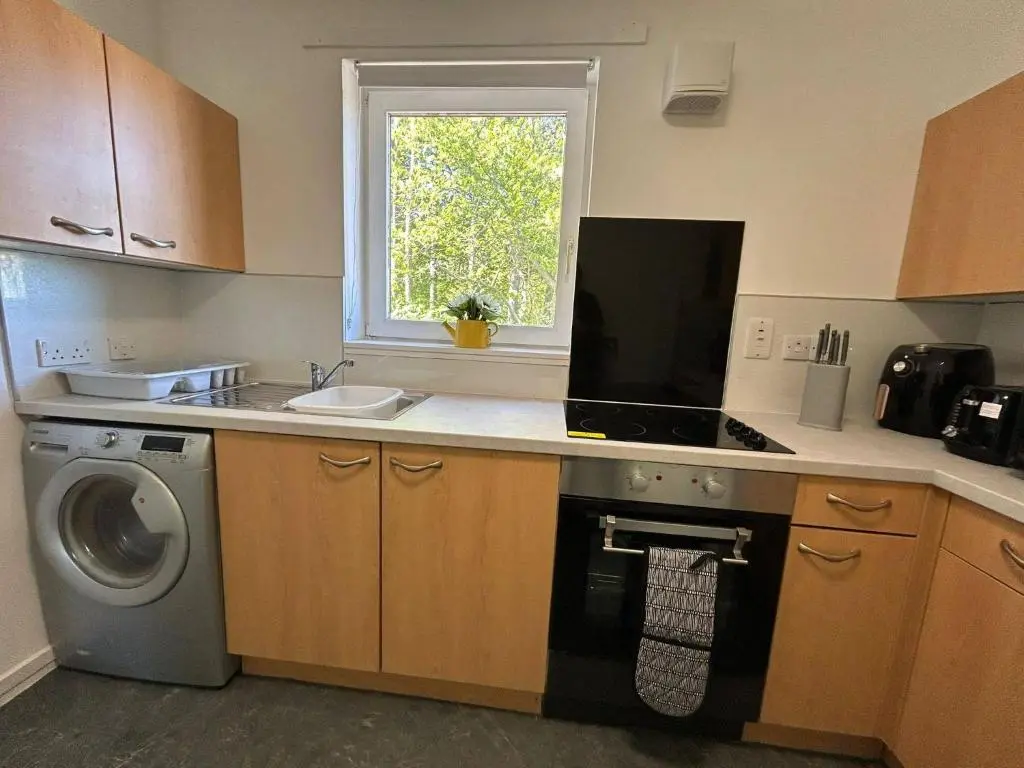 a kitchen with a sink and a washing machine at Two bedroom cottage in Lumsden - Contractors in Huntly
