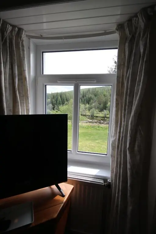 a flat screen tv sitting in front of a window at Stag View in Garve