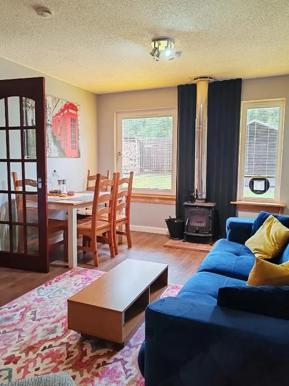 a living room with a blue couch and a table at Private Holiday Home in Inverness with Free Parking l Sleeps 4 in Dalneigh