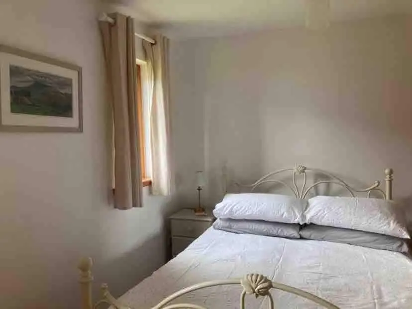 a bedroom with a white bed and a window at East Cottage, Brodie in Dyke