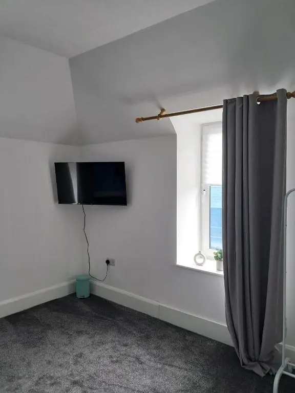 a white room with a television and a window at Granny's Hoose in Wick