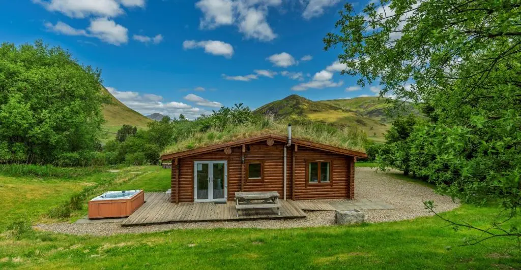 a small wooden cabin with a grass roof at Finest Retreats - Cragdhu Log Cabin in Glenshee