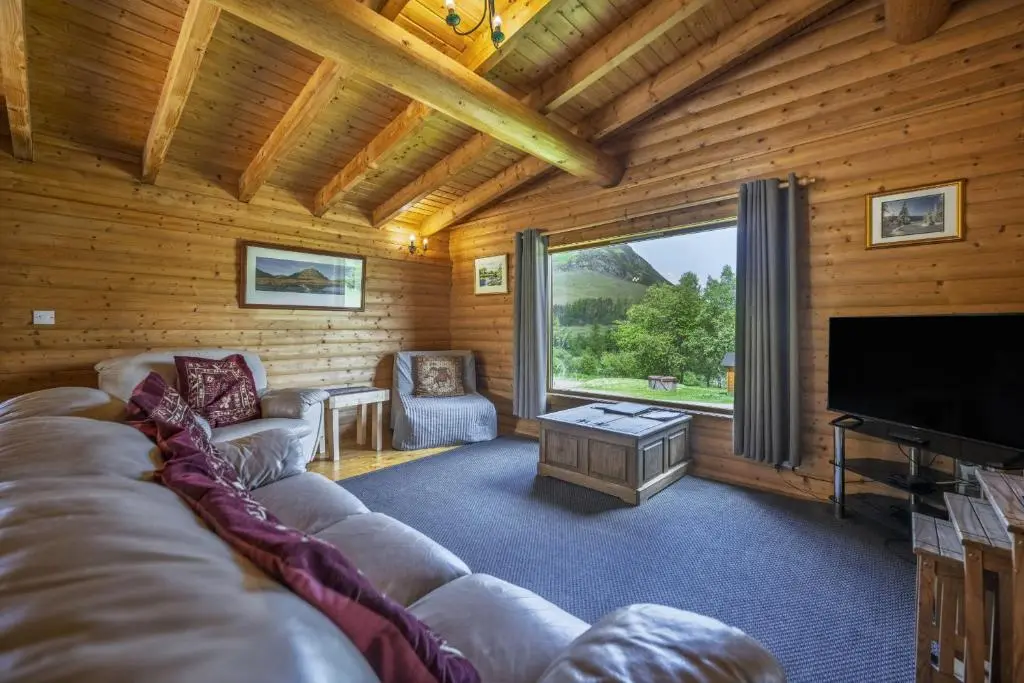 a living room with a couch and a flat screen tv at Finest Retreats - Cragdhu Log Cabin in Glenshee