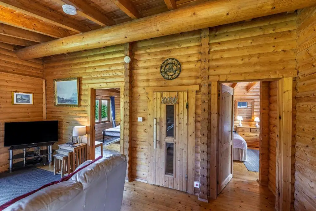 a living room with a couch and a tv at Finest Retreats - Cragdhu Log Cabin in Glenshee