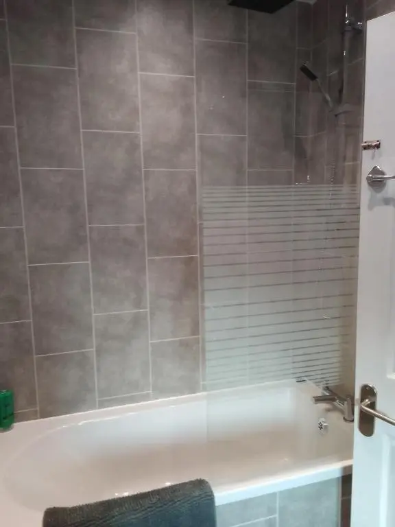 a bathroom with a bath tub with a glass shower at Cosy Crown 1 bedroom flat for up to 4 guests in Inverness