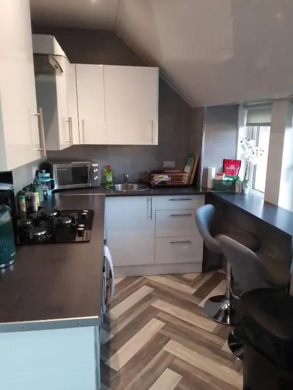 a kitchen with white cabinets and a black counter top at Cosy Crown 1 bedroom flat for up to 4 guests in Inverness