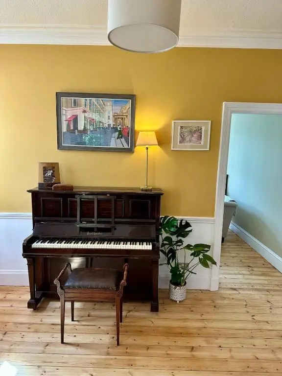 a living room with a piano and a lamp at Ladies Walk - Stunning Riverfront Home in Inverness