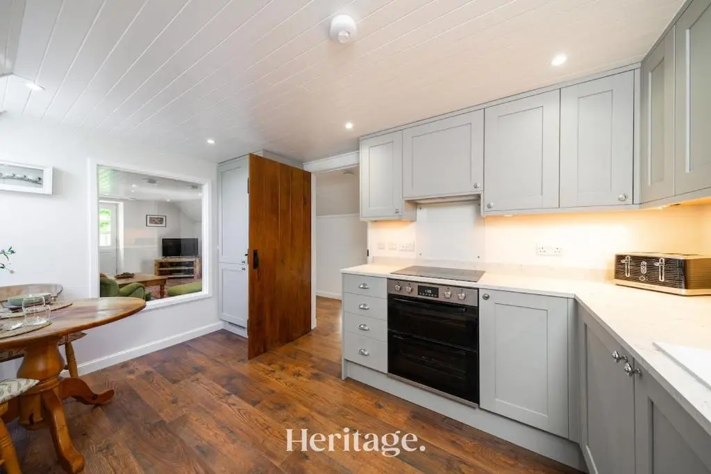 a kitchen with white cabinets and a wooden table at The Byre, Countryside Home in Tough