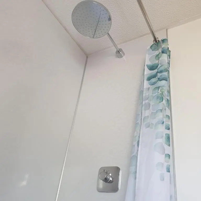 a shower with a blue shower curtain and a mirror at 1 Bed Apartment Inverness with City Views in Inverness