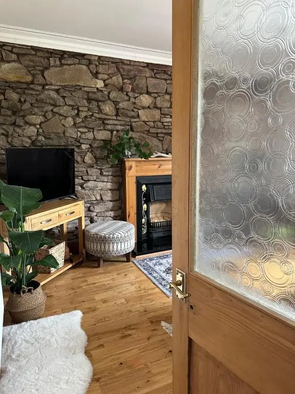 a door to a living room with a stone fireplace at Serendipity The Apartment in South Kessock