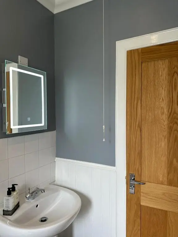 a bathroom with a sink and a wooden door at Serendipity The Apartment in South Kessock