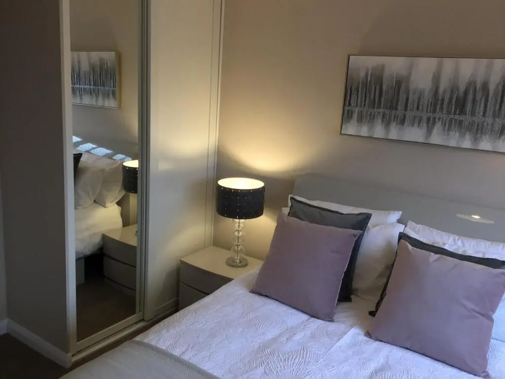 a bedroom with a bed with purple pillows and a mirror at Newly refurbished 3 bed house in Inverness