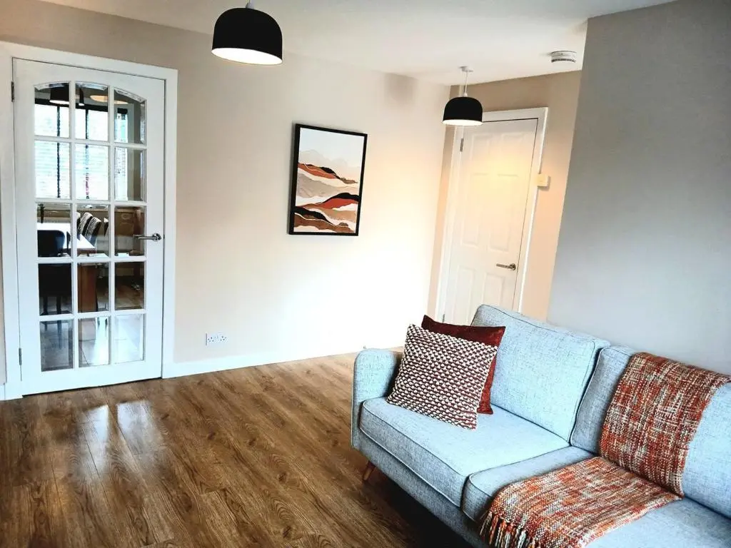 a living room with a blue couch and wooden floors at Newly refurbished 3 bed house in Inverness