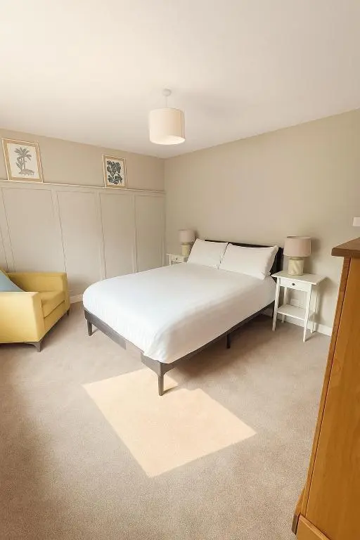 a bedroom with a white bed and a yellow chair at Flat by the Firth - Stay in the heart of Nairn in Nairn