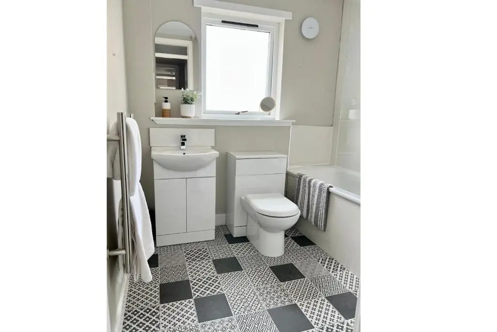 a white bathroom with a toilet and a sink at Flat by the Firth - Stay in the heart of Nairn in Nairn