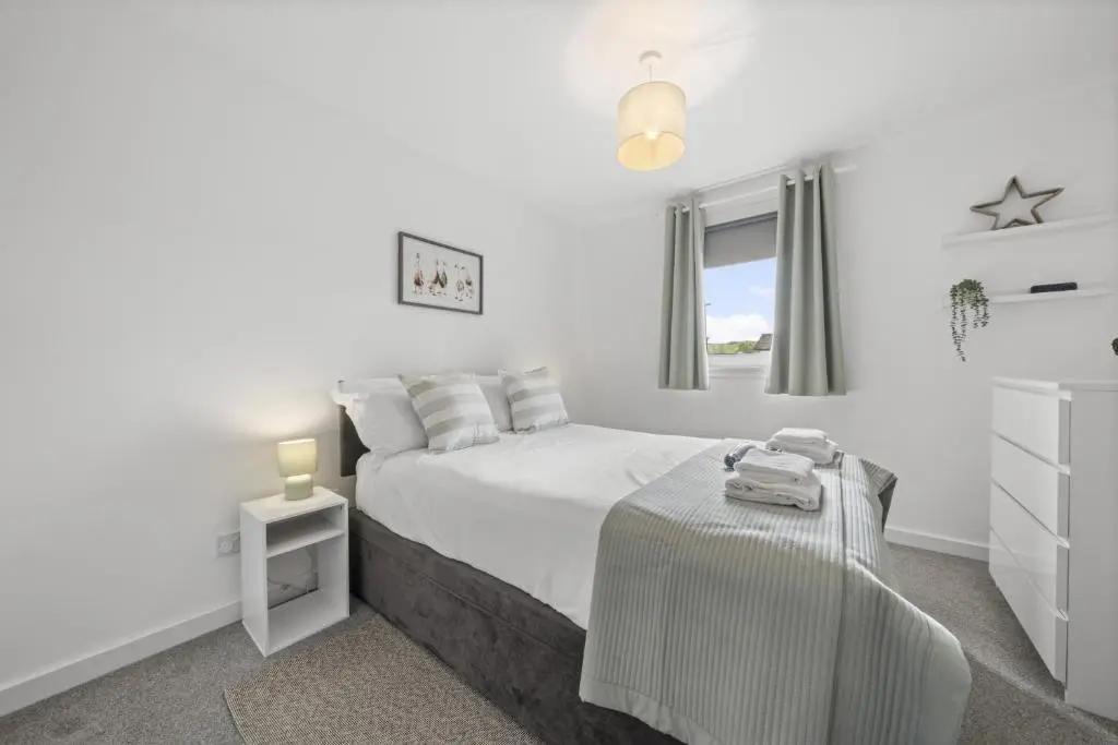 a white bedroom with a bed and a table at Heather 3 Bedroom House - Inverness in Inverness