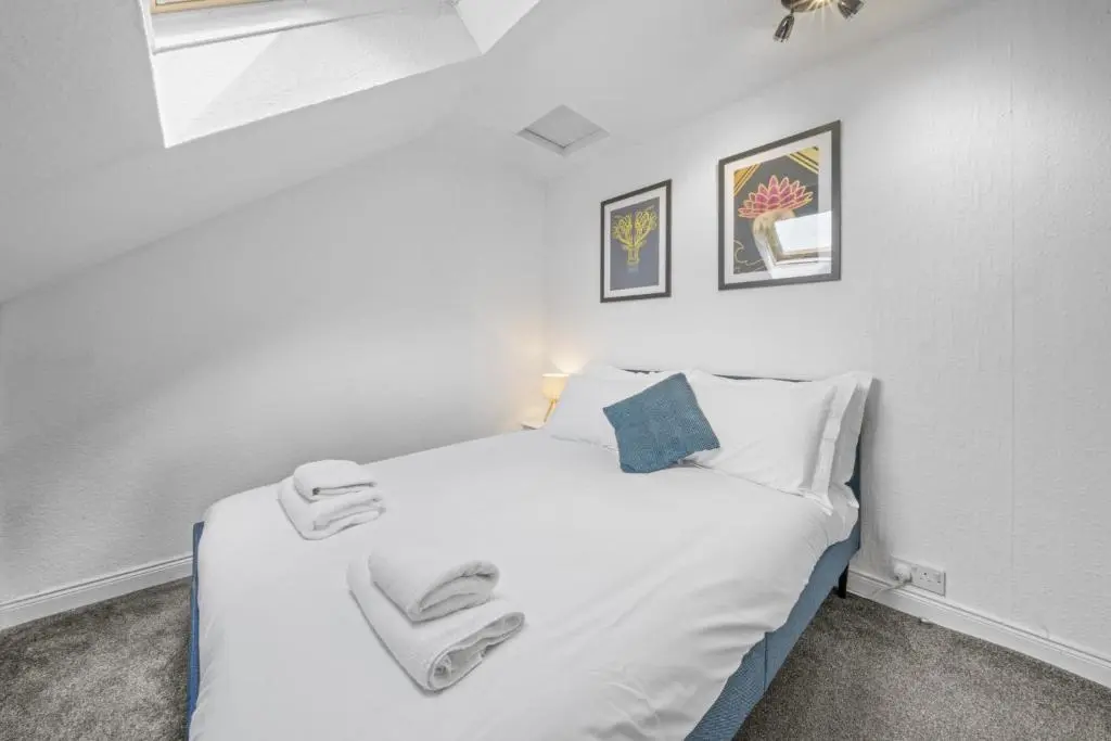 a bedroom with a white bed with two towels on it at Crown 3 Bedroom Apartment - Inverness in Inverness