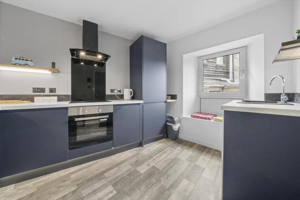 a large kitchen with blue cabinets and a sink at Crown 3 Bedroom Apartment - Inverness in Inverness