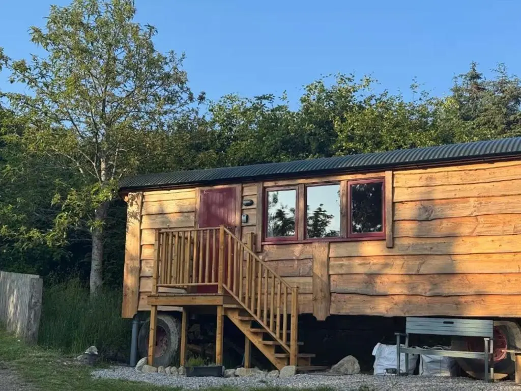 a wooden cabin with a staircase and windows on it at Holiday Home Shepherds Hut by Interhome in Balnain