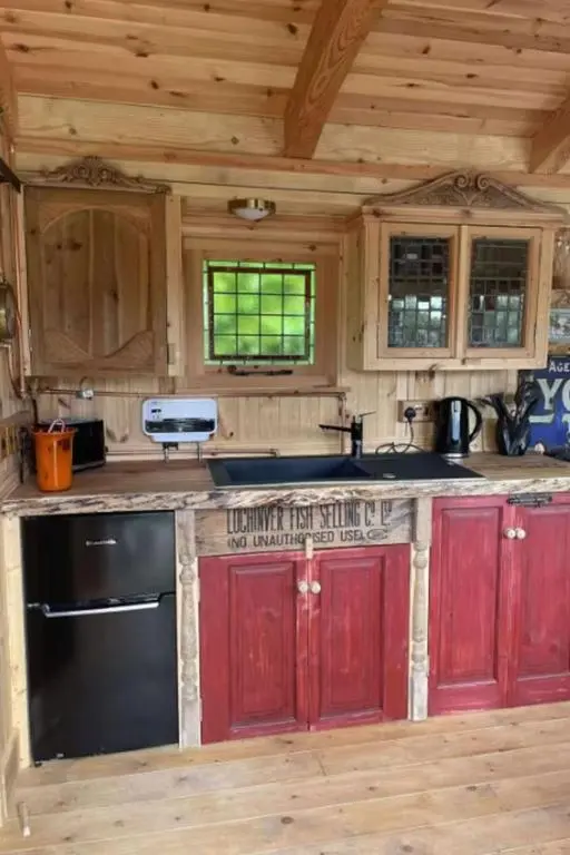 a kitchen with red cabinets and a black stove at Holiday Home Shepherds Hut by Interhome in Balnain