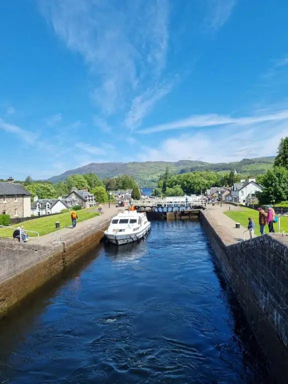 a boat in a canal in a town at Bailem Lodge at Loch Ness ADULTS ONLY in Fort Augustus