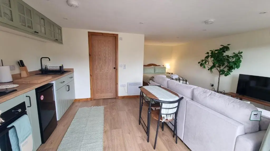 a living room with a couch and a kitchen at Bailem Lodge at Loch Ness ADULTS ONLY in Fort Augustus
