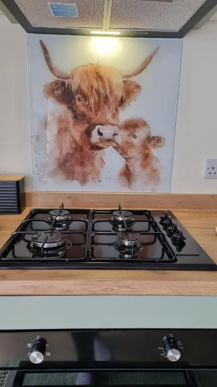 a painting of a cow on the wall above a stove at Bailem Lodge at Loch Ness ADULTS ONLY in Fort Augustus