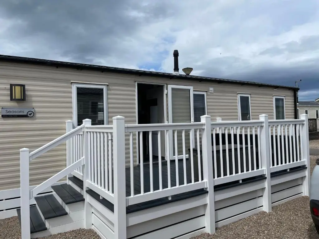 a mobile home with a white railing and a porch at J4 Lossiemouth Bay Caravan Park in Lossiemouth