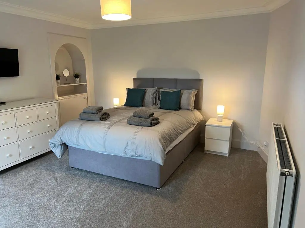 a bedroom with a bed with blue pillows and a tv at 1 Links Place in Nairn