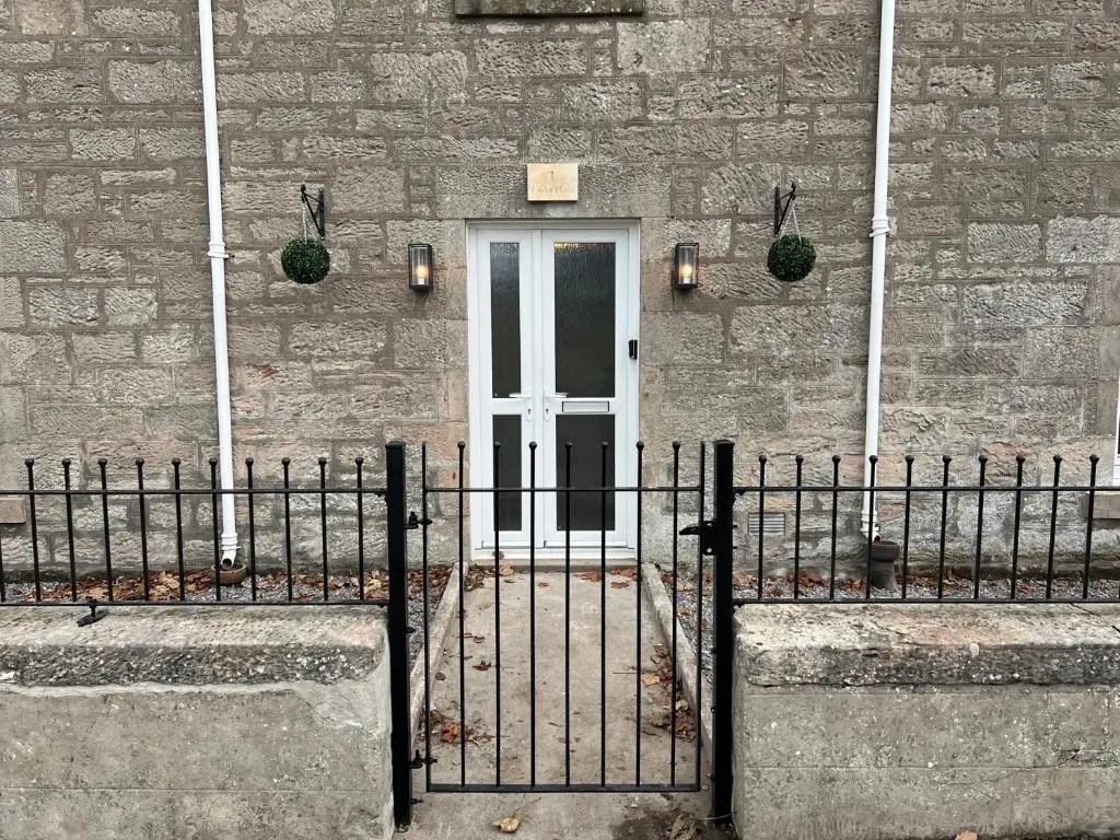 a gate in front of a building with a door at 1 Links Place in Nairn