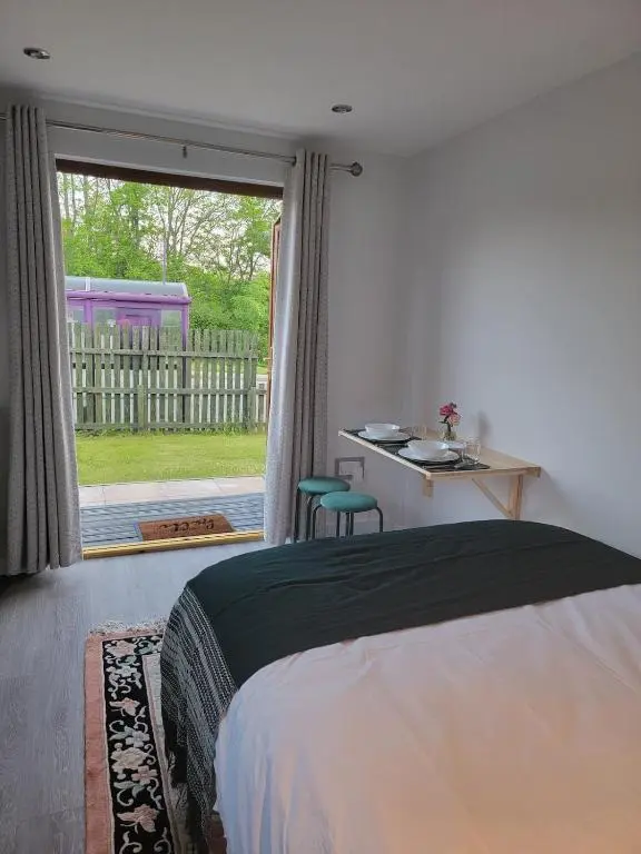a bedroom with a bed and a view of a yard at 'Wee Smiddy' Shepherd's Hut - Sauna - Yoga - Wild Swim in Skye of Curr