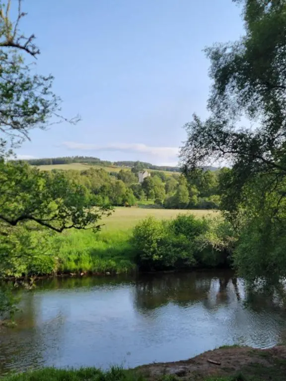 a river with trees and a field in the background at 'Wee Smiddy' Shepherd's Hut - Sauna - Yoga - Wild Swim in Skye of Curr