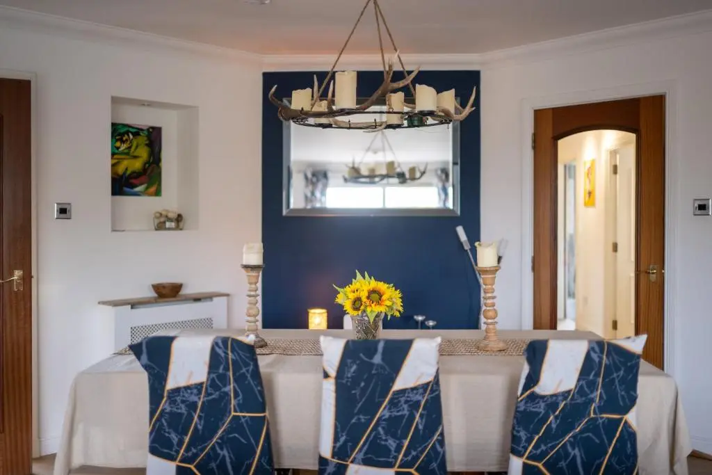a dining room with a table with a blue wall at Lochnomore - A Luxury Home With Magnificent Views in Nairn