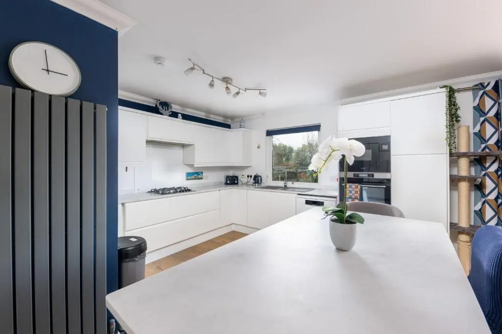 a kitchen with white cabinets and a clock on the wall at Lochnomore - A Luxury Home With Magnificent Views in Nairn