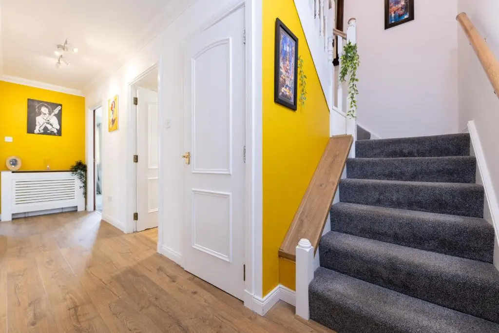 a hallway with stairs and a yellow wall at Lochnomore - A Luxury Home With Magnificent Views in Nairn
