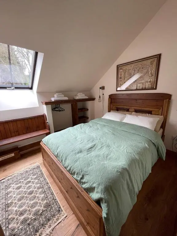 a bedroom with a wooden bed with a green comforter at Church Brae in Tomatin