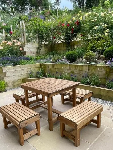 a wooden picnic table and benches in a garden at Church Brae in Tomatin