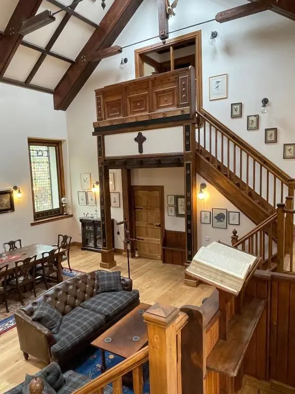 a large living room with a staircase and a table at Church Brae in Tomatin