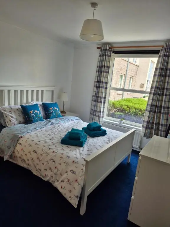 a bedroom with a bed with blue pillows and a window at Riverside Gardens in Dalneigh